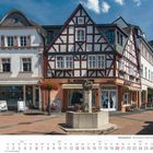 Kalenderseite Juni 2027. Datum in Wochen und Tagen. Fachwerkhaus mit der Aufschrift "Anno Domini 1721", Blumen und einem Brunnen.