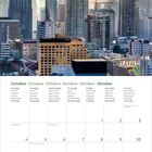 Kalender für Oktober 2027 mit Wochentagen in mehreren Sprachen. Stadtansicht von Hochhäusern bei Sonnenuntergang.