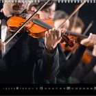 Kalenderblatt Juni, zeigt Musiker in Anzügen beim Geigenspiel in harmonischer Anordnung.