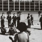 "Skopje, North Macedonia" und "The Humanitarian Gift" sind darauf zu lesen. Kinder spielen vor einem Gebäude mit großen Fenstern.