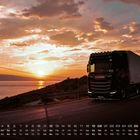 Kalenderdaten unten, Sonnenuntergang über dem Meer, ein großer LKW auf einer Küstenstraße.