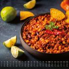 Kalenderübersicht Juni mit Wochentagen. Eine Schüssel Chili con Carne, garniert mit Koriander und Tortillachips.