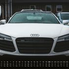 „Audi R8 6“ steht rechts unten, Kalender darunter. Nahaufnahme eines weißen Autos im Vordergrund bei Regen.