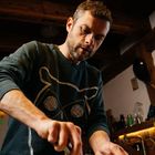 Ein Mann rührt in einem Topf. Er trägt ein Sweatshirt mit einer großen Eulenzeichnung darauf. Die Umgebung ist eine Küche.