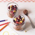 Zwei Gläser mit Schokoladenmousse, Beeren und Walnüssen. Daneben farbige Stifte und eine Zeichnung der Sonne.