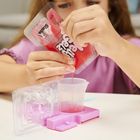 Auf einer Packung steht "Magic Mixies". Ein Kind gießt eine rosa Flüssigkeit in ein Plastikgefäß.