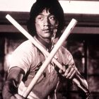 Ich erkenne keine lesbaren Texte. Ein Mann mit Kurzarmshirt hält zwei Holzstäbe gekreuzt.