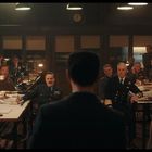 Viele Männer in Militäruniformen sitzen und stehen um einen großen Tisch in einem Raum mit hölzerner Einrichtung.