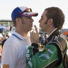 Zwei Männer stehen sich gegenüber; einer hat "26" auf dem Ärmel, der andere trägt "Perrier" und "NASCAR" auf der Jacke.