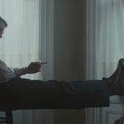 Zwei Männer sitzen entspannt im Gegenlicht. Einer sitzt auf einem Stuhl mit den Füßen auf dem Tisch, der andere lehnt an der Wand.