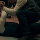 Zwei Personen ringen auf dem Boden, umgeben von liegenden Menschen und einem Leiterwagen im Hintergrund.