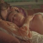 Ich kenne die Texte nicht. Eine Frau liegt mit geschlossenen Augen auf einem Sofa und wird von einer anderen Person zärtlich umarmt.