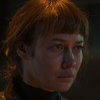 Ich weiß nicht, wer die Person ist. Sie hat kurzes, bräunliches Haar und schaut ernst. Der Hintergrund ist dunkel.