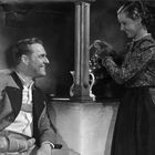 Ein Mann lächelt eine Frau an, die Kaffee einschenkt. Beide in traditioneller Kleidung.