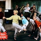 Text: "SO TOLL wie anno dazumal." Eine Gruppe von Menschen tanzt fröhlich, begleitet von Live-Musikern im Hintergrund.