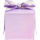 Kein Text erkennbar. Ein quadratisches Geschenk, lila verpackt, mit einer dekorativen Schleife oben.
