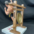 Ein muskulöser Mann tritt mit dem Bein in die Luft, vor einem Gestell mit einem runden Gong.