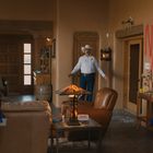 An der Wand steht in roter Farbe "NO JUSTICE". Zwei Polizisten stehen in einem Wohnzimmer, dazwischen ein Mann mit Cowboyhut.