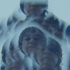 Gesichter eines Mannes vielfach kaleidoskopartig vervielfacht vor blauem Hintergrund.