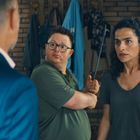 Zwei Personen stehen in einer Tür. Der Mann im Polohemd hält einen Gehstock. Beide wirken ernst. Ein Mann im Anzug steht davor.