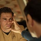 Ein Mann in beiger Uniform mit einem Sternlogo wird von einer Hand am Gesicht berührt. Er wirkt nachdenklich.