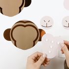 Ausschnitt eines Affen-Gesichts aus Papier. Hände halten Form, die mehrmals in anderen Farben zu sehen ist.