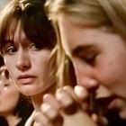 Vier Personen, zwei im Fokus. Eine Frau sieht besorgt zur Seite, während eine andere betet, die Hände gefaltet.