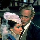 Ein Mann und eine Frau in historischer Kleidung, sie trägt einen aufwendigen Hut. Beide schauen ernst.