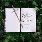 „The Queen of Nothing“ von Holly Black; ein aufgeschlagenes Buch, darauf ein Schwert, umgeben von grünen Blättern.