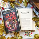 Buchcover: "The Gilded Blade", "Chapter 1: Jameson". Goldene Blätter, Spielkarten und Edelsteine umrahmen die Szene.