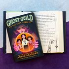 "Ghost Guild: The Lost Three" und "Annie Barrows" steht auf einem Buchcover. Illustration mit drei Figuren und Kristallkugel.