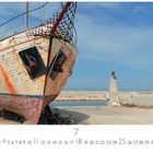 "Hafenimpression" steht oben links. Ein altes, rostiges Schiff steht auf Land. Im Hintergrund sind zwei Leuchtsäulen.