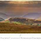 Text oben: "Golway". Unten Monatsübersicht mit Zahlen. Landschaft mit Hügeln im Sonnenlicht und Wolken am Himmel.