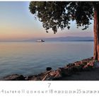 "Morgenstimmung", Juli-Kalenderblatt, ruhiger See mit Schiff, Baum im Vordergrund, Berge am Horizont.