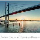 Text: „Rügenbrücke“, Datumsleiste bis 31, „CASARES EDITION“. Eine Brücke überquert ein Gewässer bei Sonnenaufgang.