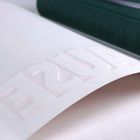 Erhabene Schrift "ERU" auf weißem Papier, Hintergrund in dunklem Grün.