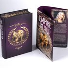 Ein Buch mit dem Titel "Empire of Blood: We Who Will Die". Auf dem Cover ist ein goldener Greif in einem Lorbeerkranz abgebildet.