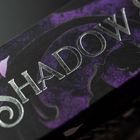 Text: "SHADOW"; silberne Buchstaben auf violett-schwarzem Hintergrund, kunstvoll gestaltet.