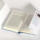 Das Buch liegt offen, Seiten mit Text. Ein Lesezeichen ragt heraus. Auf dem Lesezeichen steht oben: "Denis Moschitto, Hamburg 1977".