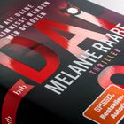 „UND ALL DEINE GEHEIMNISSE WERDEN MIR GEHÖREN“ steht vorne. Thriller von Melanie Raabe, mit rotem und weißem Text.