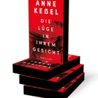 Ein Stapel von Büchern, Titel: "Die Lüge in Ihrem Gesicht" von Anne Keßel. Rotes Cover, stilisiertes Haarmotiv.