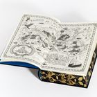 "Empyreios" und "Volier." Eine kunstvolle, schwarz-weiße Karte in einem Buch mit reich verziertem, goldenem Umschlag.