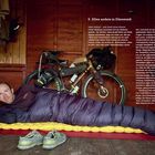 "9. Alles anders in Dänemark" ist die Überschrift. Ein Mann liegt in einem Schlafsack vor einem beladenen Fahrrad in einer Hütte.