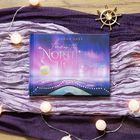 Buchcover: "Finding the Northern Lights" von Sarah Saxx auf buntem Tuch. Lichterkette und Steuerrad-Deko.
