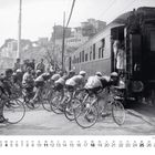Tour de France 1950, Mailand - San Remo. Radfahrer neben einem Zug, Zuschauer im Hintergrund, Gebäude auf einem Hügel.