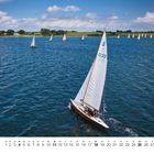 Kalenderseite für Juli mit Segelbooten auf einem See, unter blauem Himmel.