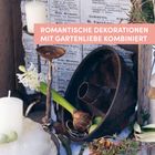 Text: "ROMANTISCHE DEKORATIONEN MIT GARTENLIEBE KOMBINIERT". Kerzen, Blumen und alte Gegenstände dekorieren eine Szene.
