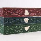 Keine Texte vorhanden. Drei Bücher mit roten, blauen und grünen floralen Mustern und stilisierten Tierköpfen auf den Buchrücken.