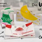 Text: "Farben erkennen und benennen. Die Welt ist bunt! Ab 3 Jahren. Ideal zur Frühförderung. Oetinger." Drei aufgestellte Kinderbücher mit Pop-Up-Elementen, darunter Mond und Clownsnase.
