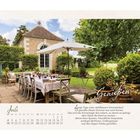 Juli-Kalenderseite mit einem Zitat über das Genießen des Sommers. Bild: Garten mit gedecktem Tisch, Sonnenschirm und Haus.